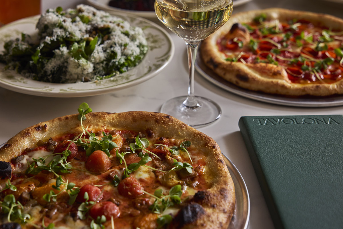 A table setting with pizza, salad, and wine.